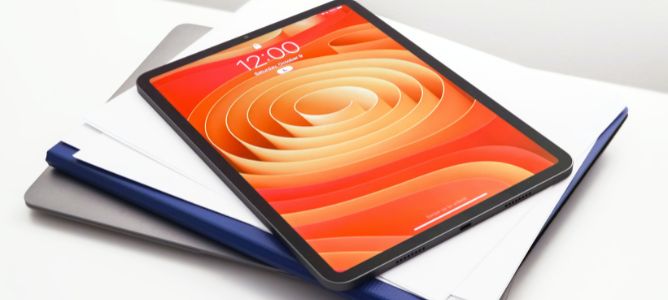 iPad tablet with an orange screen face sitting on top of a laptop. iPad tablet with an orange screen face sitting on top of a laptop.