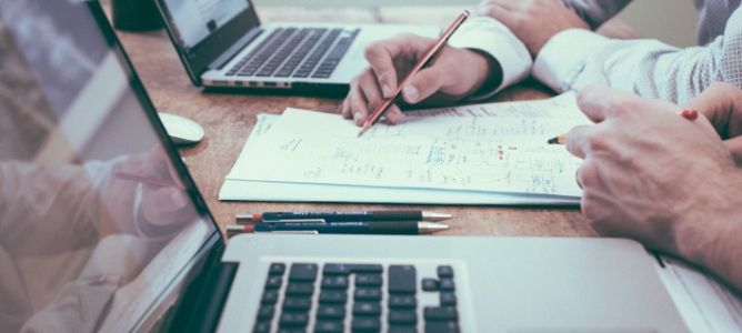 Students writing on paper with a pencil next to a laptop. Students writing on paper with a pencil next to a laptop.