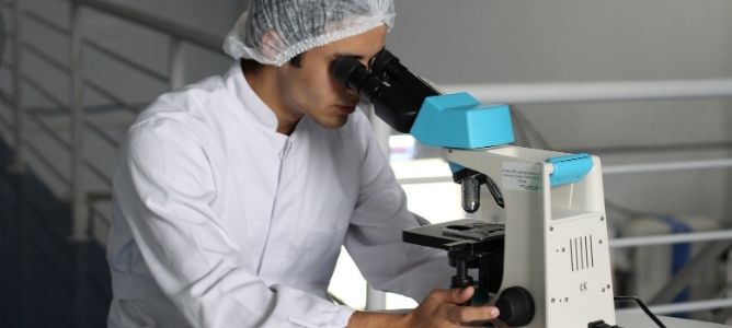 Lab technician looking through microscope. Lab technician looking through microscope.