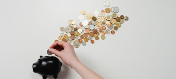 Person putting change in piggy bank.