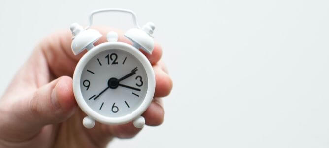 Hand holding a tiny white clock.