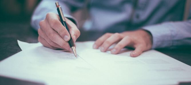 Person filling out forms with a pen. Person filling out forms with a pen.