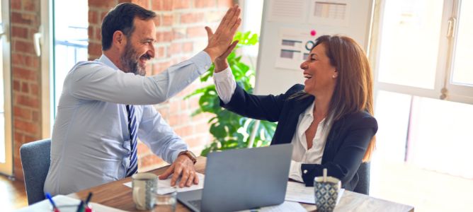 Man and woman giving a high-five in an office.