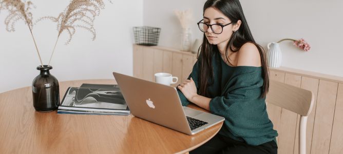 Girl with Apple laptop sitting at table. Girl with Apple laptop sitting at table.