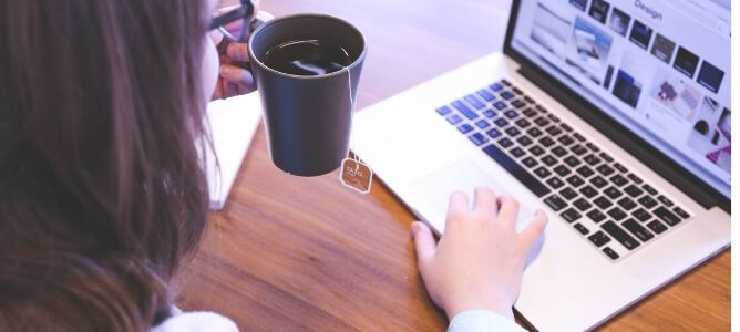 Woman on computer drinking tea.