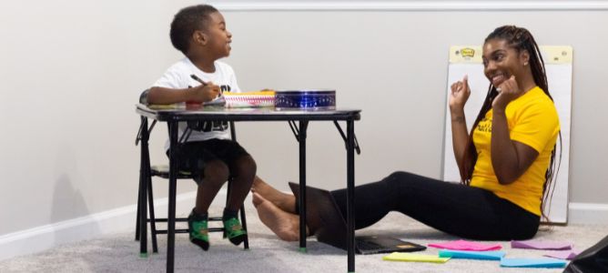 Woman sitting on floor looking at child sitting at a table. Woman sitting on floor looking at child sitting at a table.
